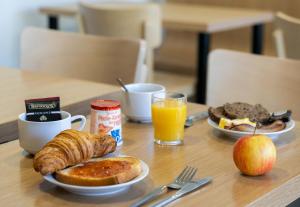 a table with two plates of breakfast foods and an apple at B&B HOTEL Lorient Lanester in Lanester