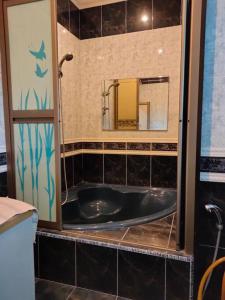 La salle de bains est pourvue d'une baignoire noire et d'un miroir. dans l'établissement The Bungalow Homestay by Cheta, à Alor Setar