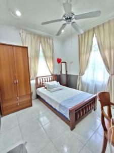 - une chambre avec un lit et un ventilateur de plafond dans l'établissement The Bungalow Homestay by Cheta, à Alor Setar