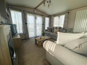 a living room with a couch and a tv at Spacious Caravan With Large Decking Area, Perfect To Enjoy The Sun, Ref 23058c in Hunstanton