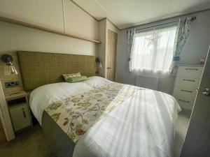 ein kleines Schlafzimmer mit einem Bett und einem Fenster in der Unterkunft Spacious Caravan With Large Decking Area, Perfect To Enjoy The Sun, Ref 23058c in Hunstanton