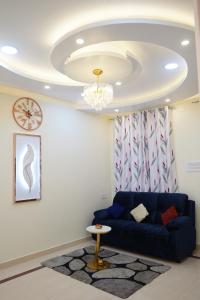 a living room with a blue couch and a chandelier at Visalam service apartment in Chennai