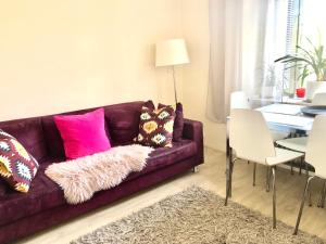 a living room with a purple couch with pink pillows at Scandinavian Desing Home 37 City Center in Kamppi in Helsinki