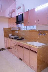 a kitchen with pink cabinets and a sink at Visalam service apartment in Chennai