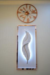 a clock and a picture of a feather on a wall at Visalam service apartment in Chennai