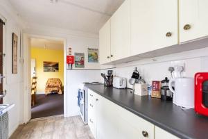 cocina con armarios blancos y encimera negra en Park View House - Sleeps 6, en York