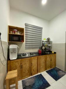 een keuken met houten kasten, een wastafel en een raam bij Razumi's Homestay in Arau