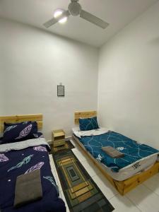 um quarto com 2 camas e uma ventoinha de tecto em Razumi's Homestay em Arau