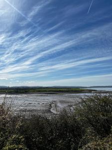 a beach with water and a blue sky and clouds at Garden Place in Clevedon