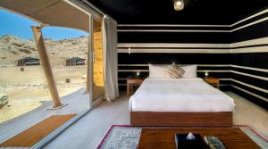 a bedroom with a bed and a view of the desert at Pura Eco Retreat, Jebel Hafit Desert Park in Al Ain