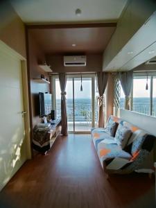 a living room with a couch and a large window at Tanglin Orchard Apartment (2BR) in Surabaya