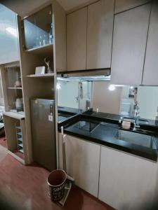 cocina con armarios blancos y nevera de acero inoxidable en Tanglin Orchard Apartment (2BR) en Surabaya