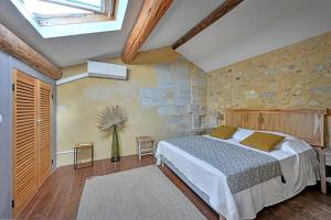 1 dormitorio con cama y pared de piedra en La Bastideto - Piscine - AC CLim - Alpilles, en Maillane