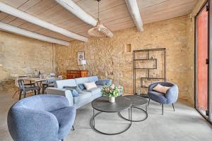 een woonkamer met een bank, stoelen en een tafel bij La Bastideto - Piscine - AC CLim - Alpilles in Maillane