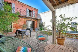 un patio al aire libre con sillas, mesa y mesa en La Bastideto - Piscine - AC CLim - Alpilles, en Maillane