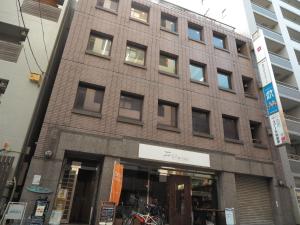 een hoog bakstenen gebouw met ramen aan een straat bij bnb+ Akihabara (Female Only) in Tokyo