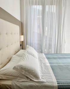 a bed with white sheets and pillows in front of a window at Albergo Degli Amici in Monterosso al Mare