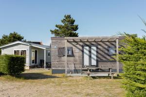 a tiny house with a porch in a yard at Vakantiepark Klein Vaarwater in Buren