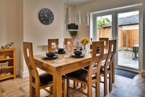 a dining room table with chairs and a clock on the wall at Finest Retreats - Shorelands in Prestatyn