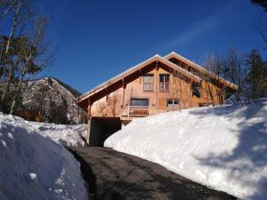 a wooden house with a snow pile in front of it at Séjour en famille dans un chalet cosy! in Briançon