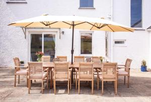 a wooden table with chairs and an umbrella at Beautiful 5-Bed House in Port Isaac in Port Isaac