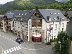 un immeuble d'appartements avec une voiture garée devant lui dans l'établissement Résidence Les Arches, à Saint-Lary-Soulan