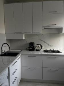 una cucina bianca con armadi bianchi e lavandino di Лучшие апартаменты в самом центре города a Čerkasy