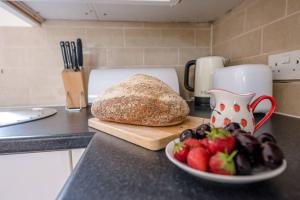 a loaf of bread and a plate of fruit on a counter at Grove Farm Bungalow and Annexe in Woodbridge