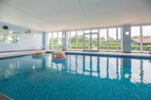 a large swimming pool with blue water in a building at Grove Farm Bungalow and Annexe, Dallinghoo in Woodbridge