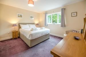 a bedroom with a bed and a table and a window at Grove Farm Bungalow and Annexe in Woodbridge