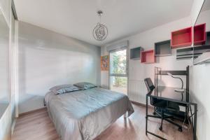 una camera con letto, scrivania e finestra di Superbe appartement à Decines a Décines-Charpieu