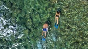 dwoje ludzi pływających w wodzie blisko brzegu w obiekcie Azienda Agricola Club Le Cannelle w mieście Talamone