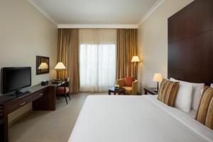سرير أو أسرّة في غرفة في Millennium Central Al Mafraq