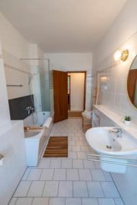uma casa de banho branca com uma banheira, um lavatório e uma banheira. em RR - Comfortable Apartment 60 qm - Central - WIFI em Magdeburg
