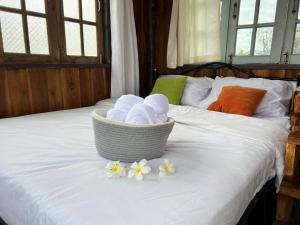 a basket of towels and flowers on a bed at Dee Tor Jai Farm Stay ดีต่อใจฟาร์มสเตย์ in Chiang Klang