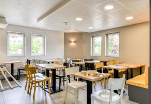 - une salle à manger avec des tables, des chaises et des fenêtres dans l'établissement B&B HOTEL Montpellier 1, à Saint-Jean-de-Védas