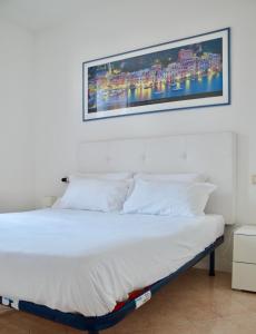 een bed met witte lakens en een foto aan de muur bij Garibaldi18 in Desenzano del Garda