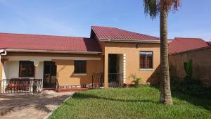 a house with a red roof and a palm tree at Residential Superb Rooms, With Wifi, Netflix, Parking, Kitchen in Kampala