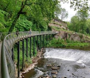 a bridge over a river with a waterfall at Immaculate 1-Bed House in Newtown Disley in Stockport