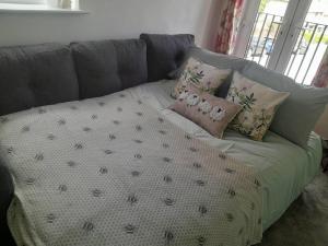 a gray couch with pillows and a blanket on it at Immaculate 1-Bed House in Newtown Disley in Stockport