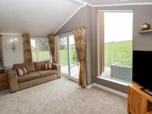 uma sala de estar com um sofá e uma grande janela em No 8 Hillcote Lodge em Cockermouth
