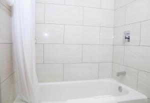 a white bathroom with a tub and a shower at Twin Pine Inn & Suites in Hinton +14 photos