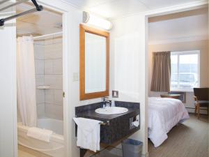 a bathroom with a bed and a sink and a mirror at Twin Pine Inn & Suites in Hinton