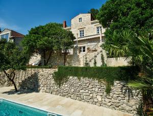 ein Haus mit einer Steinmauer neben einem Pool in der Unterkunft Villa Lemonia in Trsteno