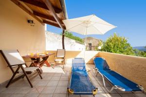 um pátio com uma mesa, cadeiras e um guarda-sol em Topolia 1 Bedroom Villa em Topólia
