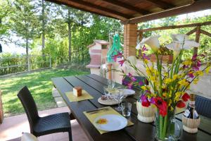 een houten tafel met bloemen op een patio bij ISA-Chalet Elena in Montescudaio, with air conditioning, on the ground floor with fenced garden in Montescudaio