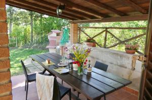 een patio met een houten tafel en stoelen bij ISA-Chalet Elena in Montescudaio, with air conditioning, on the ground floor with fenced garden in Montescudaio +7 foto's