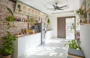 a kitchen with white cabinets and a brick wall at Sleepy Nomad Guesthouse in Malacca