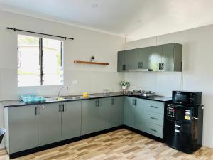 a kitchen with gray cabinets and a black refrigerator at Samah Apartments in Mba