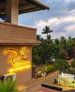 a restaurant with a sign on the side of a building at Riva Gold Coast in Candolim